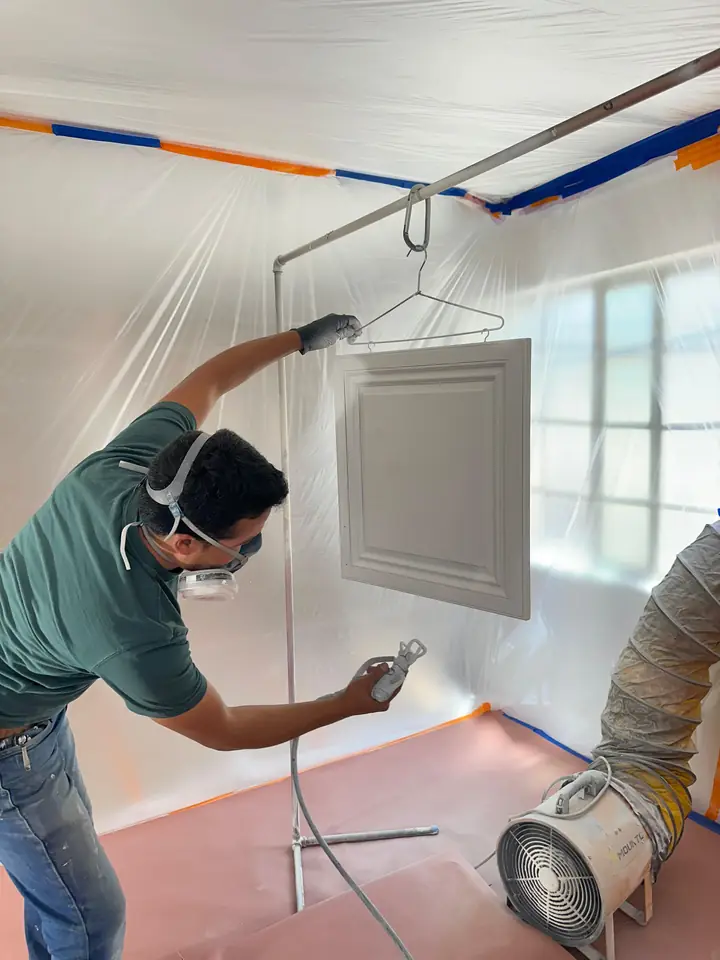 Painter sanding and prepping a wall surface before painting