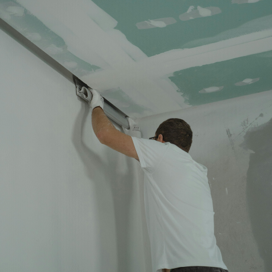 A man works meticulously on drywall installation during a house renovation.